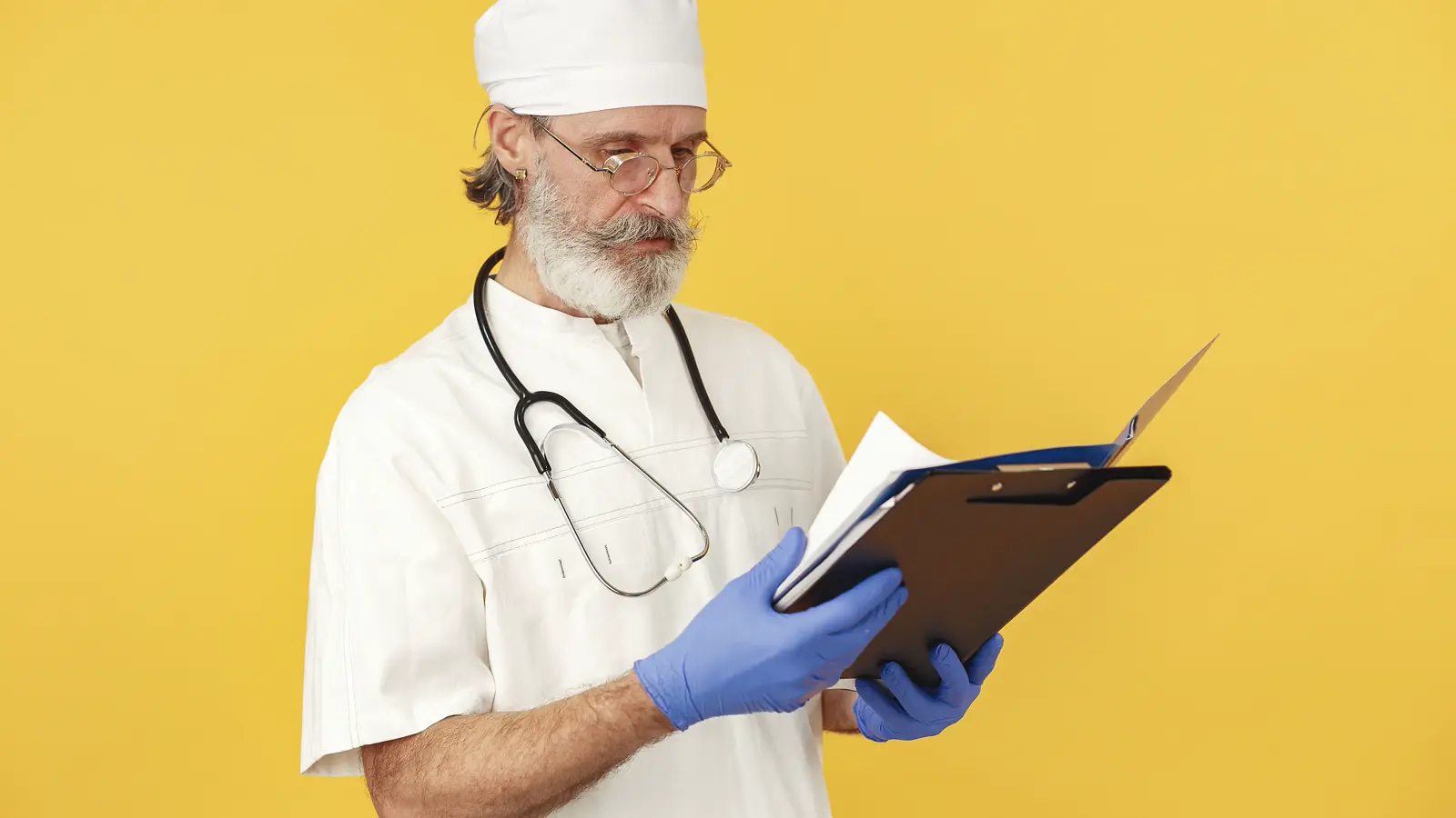 Médico de jaleco branco analisa documentos em prancheta, representando a cobrança da anuidade atrasada do CRM