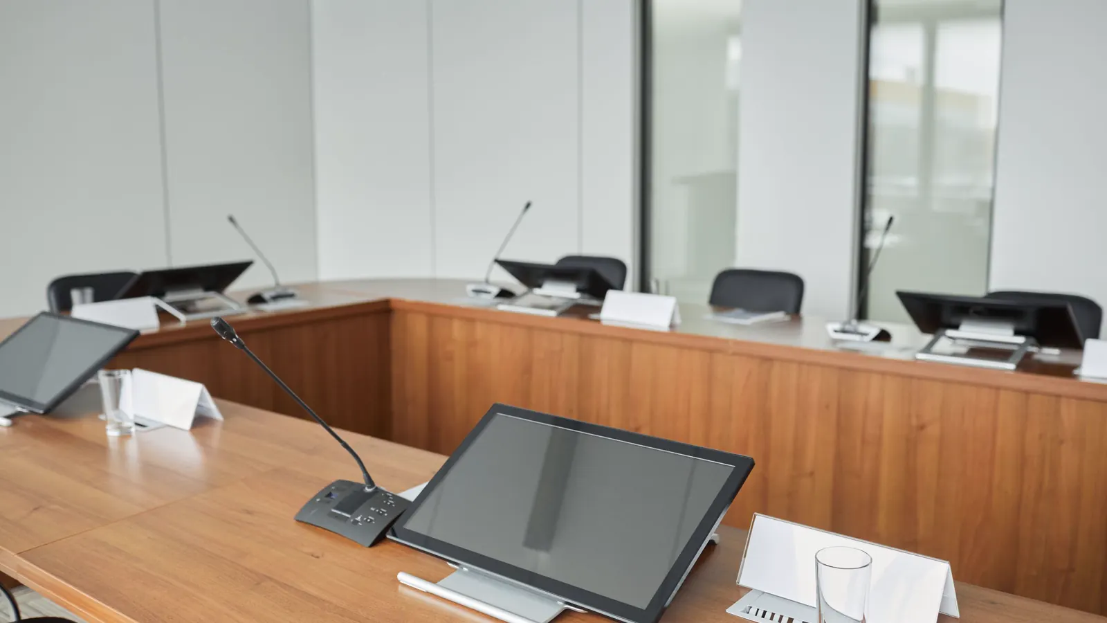Sala de audiência com mesa em U, microfones e cadeiras vazias, como as usadas na instrução do processo ético no CRM