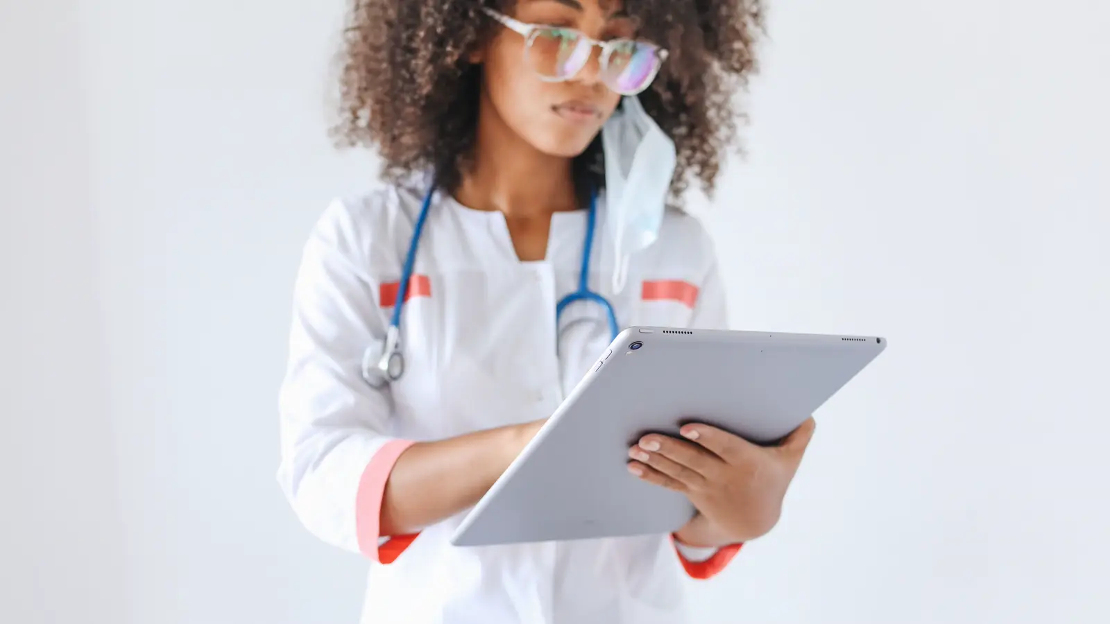 Médica consultando a agenda em tablet dentro de consultório, representando o médico que atende em clínicas de mais de um estado