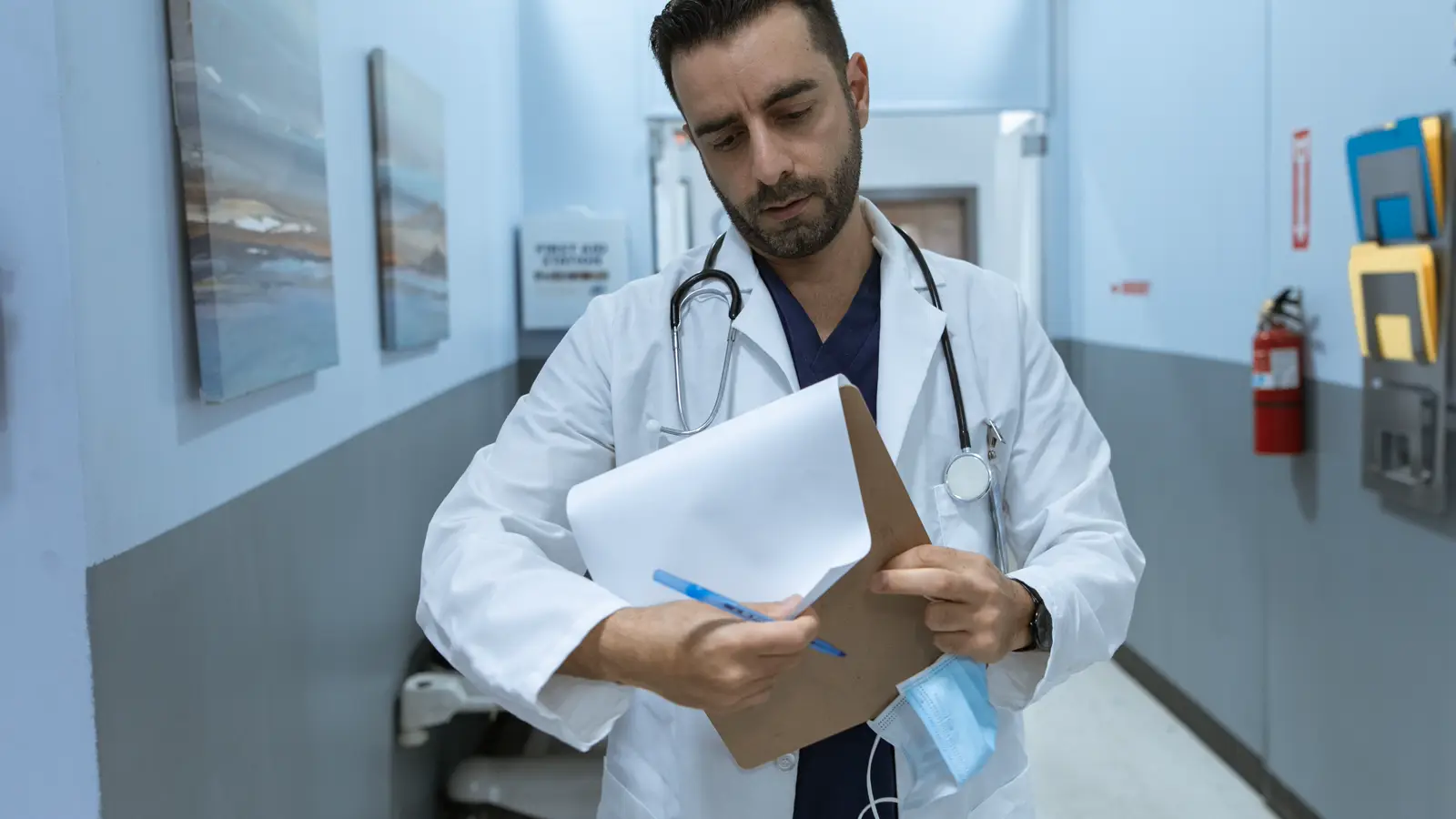 Médico em corredor de hospital anotando em prancheta, representando o preenchimento do livro-caixa para deduzir despesas no Imposto de Renda