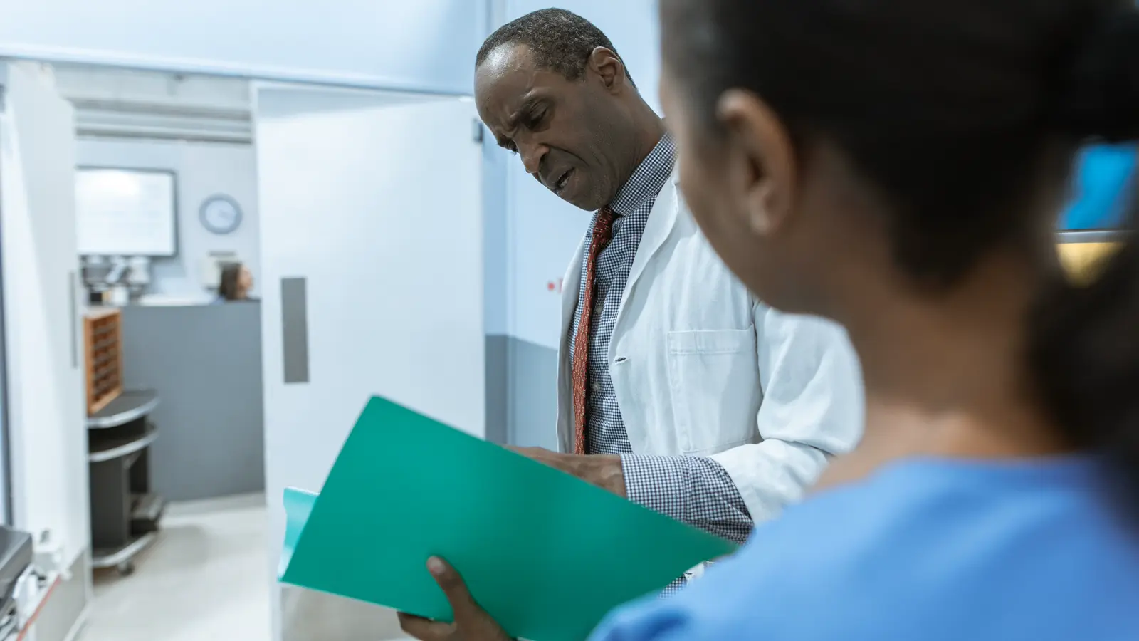 Médico e equipe analisando prontuário em pasta, representando a indicação do encarregado de dados (DPO) na clínica pela LGPD