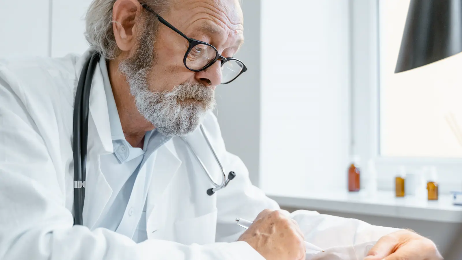 Médico de jaleco branco e estetoscópio analisa documento com atenção em consultório
