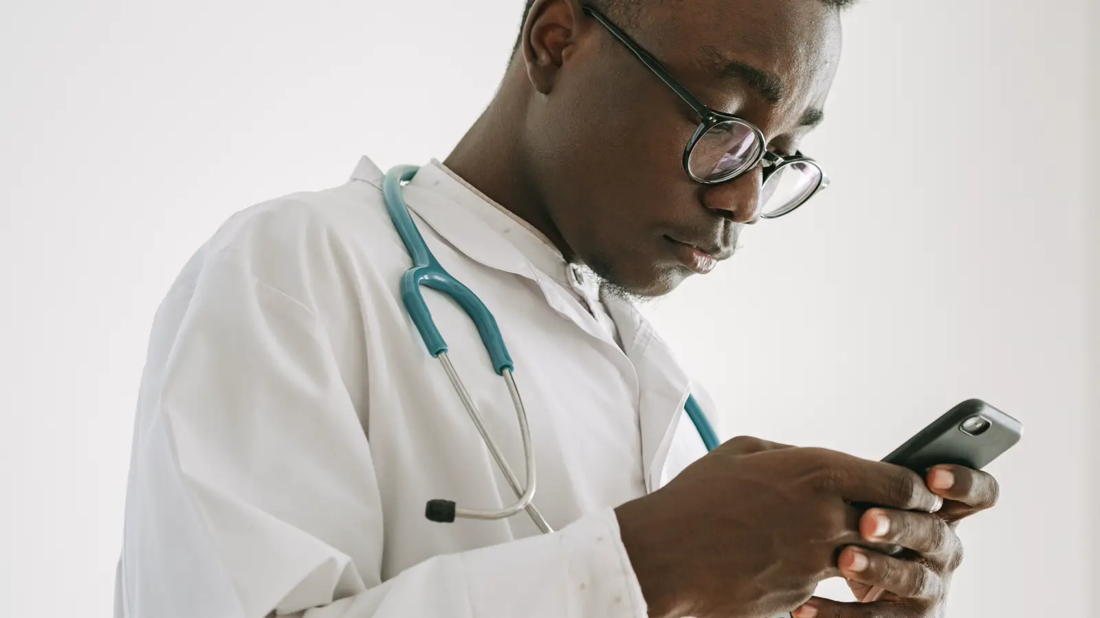 Médico digitando mensagem no celular para documentar atendimento por WhatsApp com paciente
