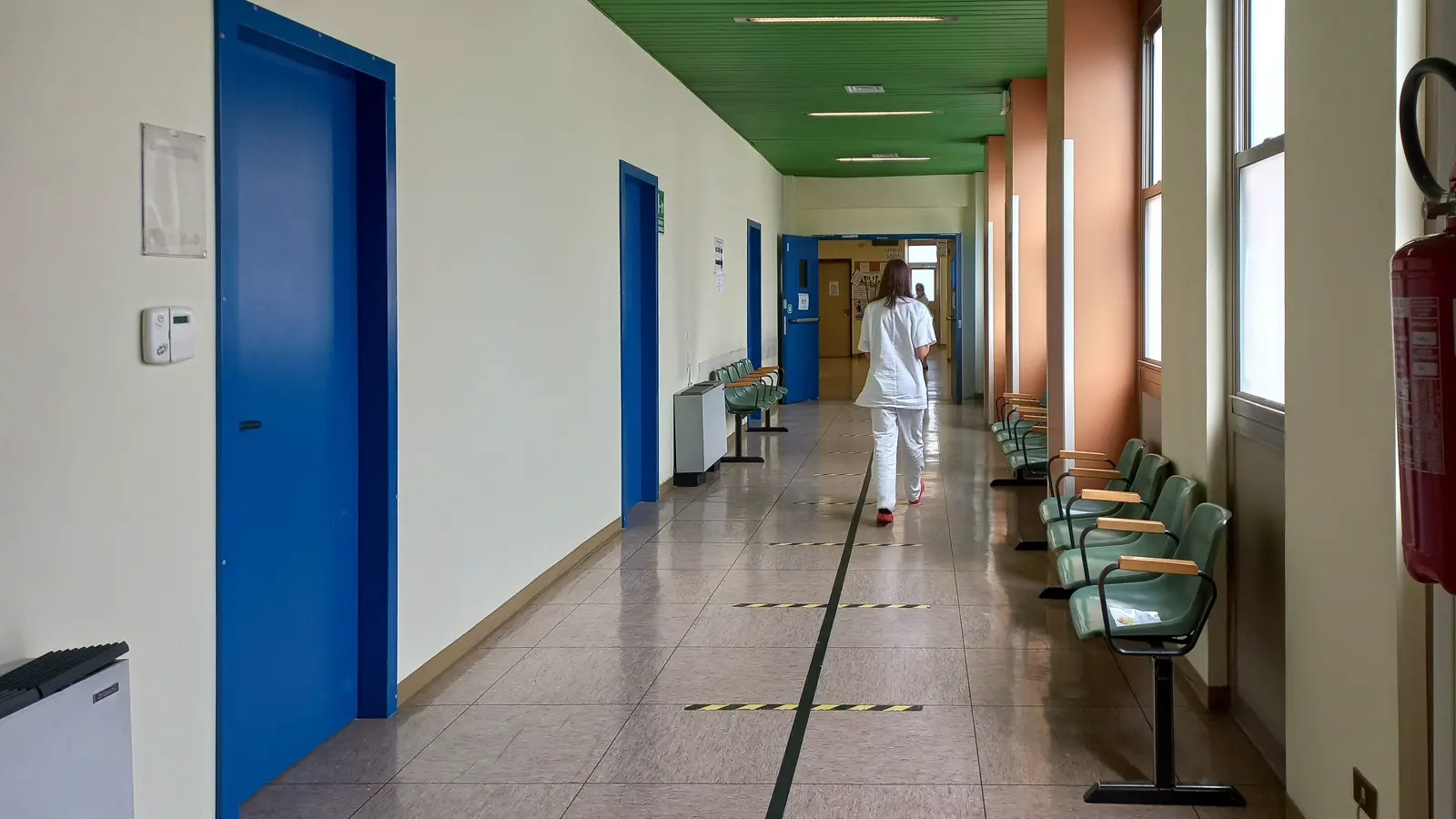 Corredor de hospital com profissional de saúde caminhando ao fundo, representando a segurança do médico durante o plantão