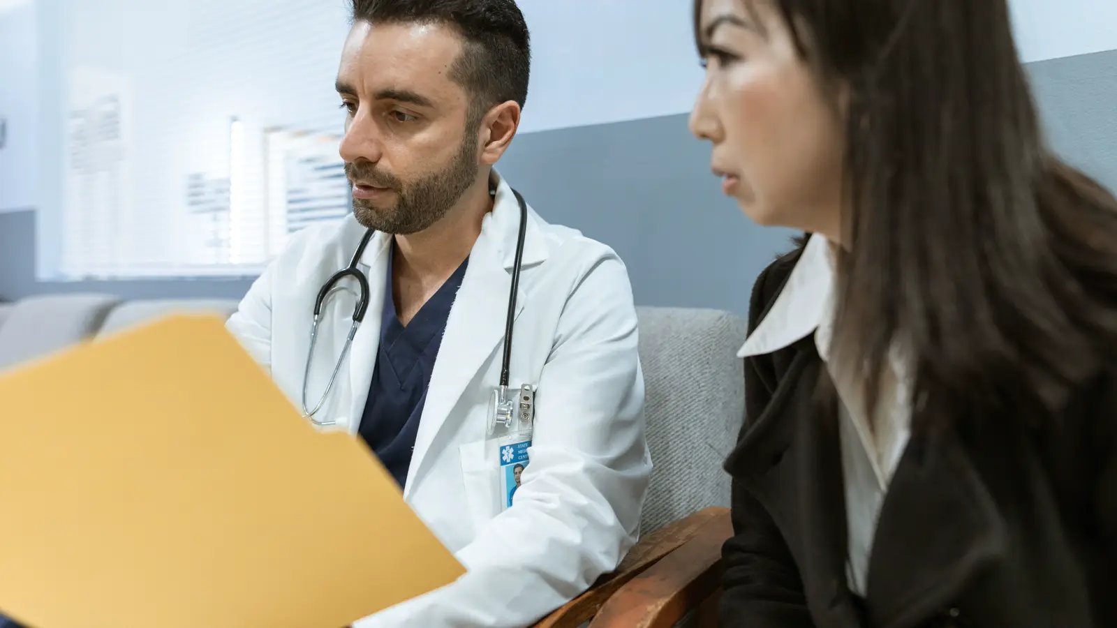 Médico com prontuário em mãos conversa com paciente sobre recusa de atendimento