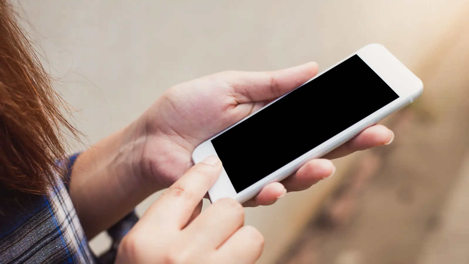 Mãos segurando um smartphone com a tela escura, ilustrando o uso de aplicativo de mensagens e chatbot no contato com o paciente