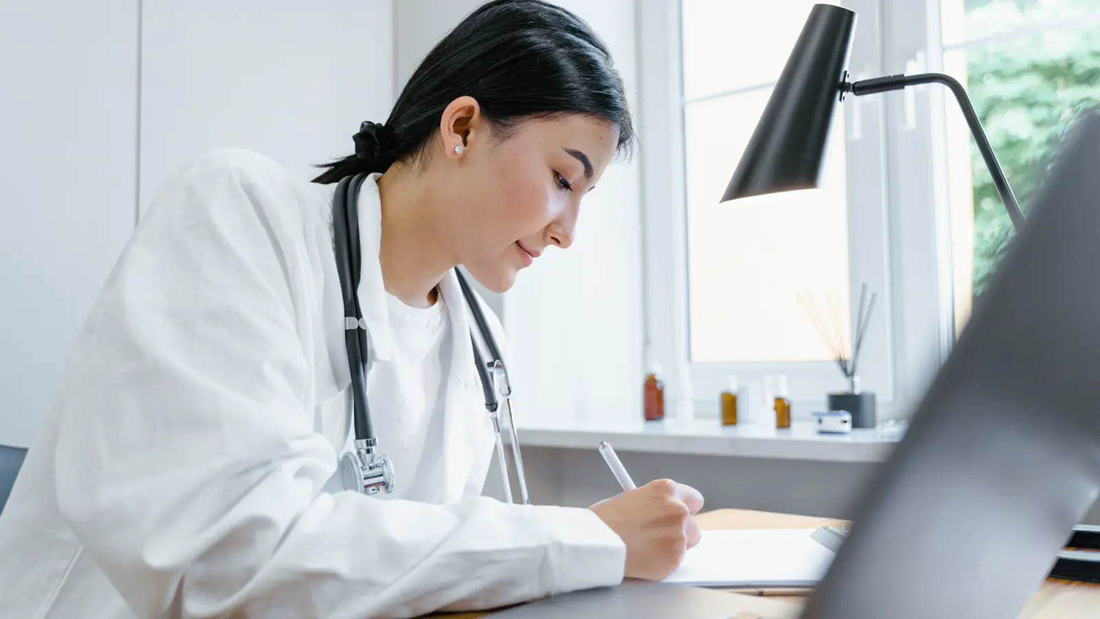 Médico sentado à mesa lendo documentos jurídicos, com estetoscópio ao lado, avaliando processos em mais de uma esfera pelo mesmo caso