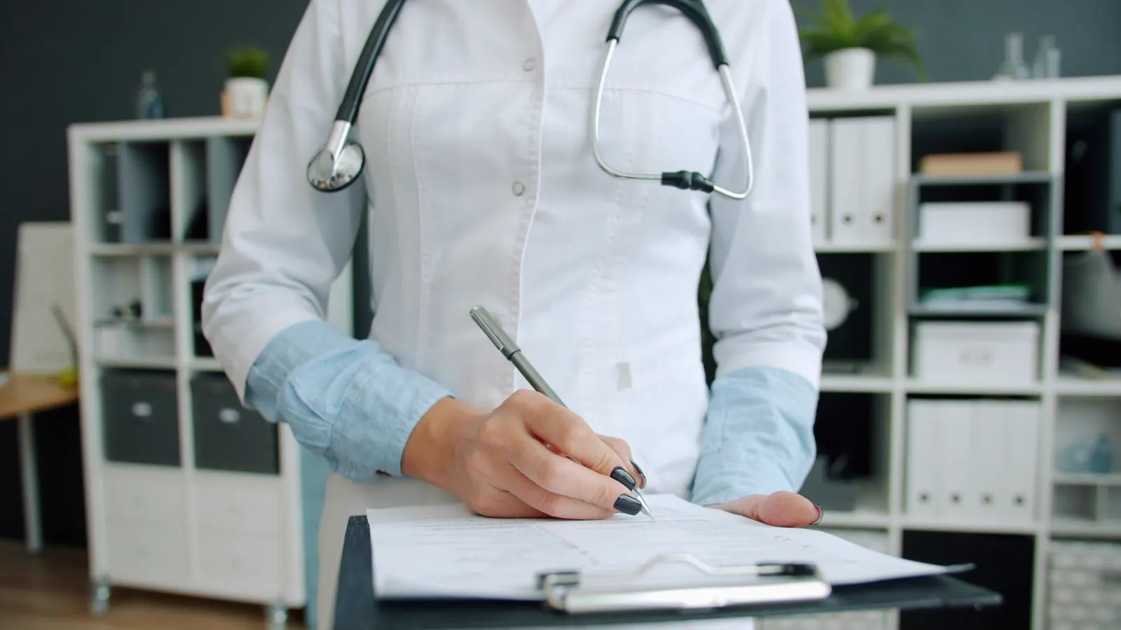Médica preenche prontuário médico em prancheta no consultório