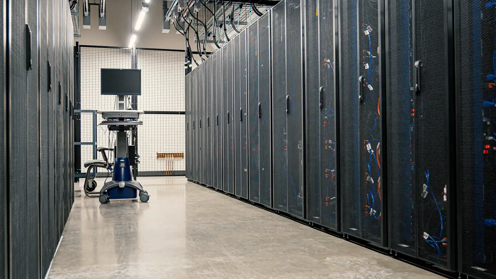 Corredor de data center com fileiras de racks de servidores, representando o armazenamento do prontuário eletrônico do paciente