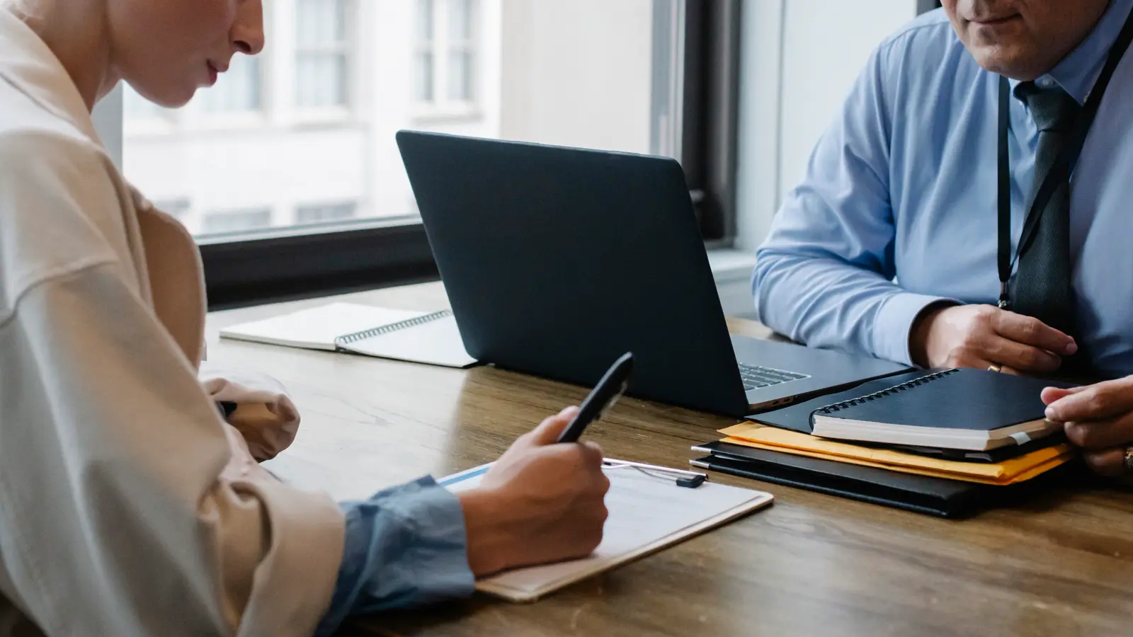 Dois sócios assinando documentos de contrato social em mesa de escritório com laptop