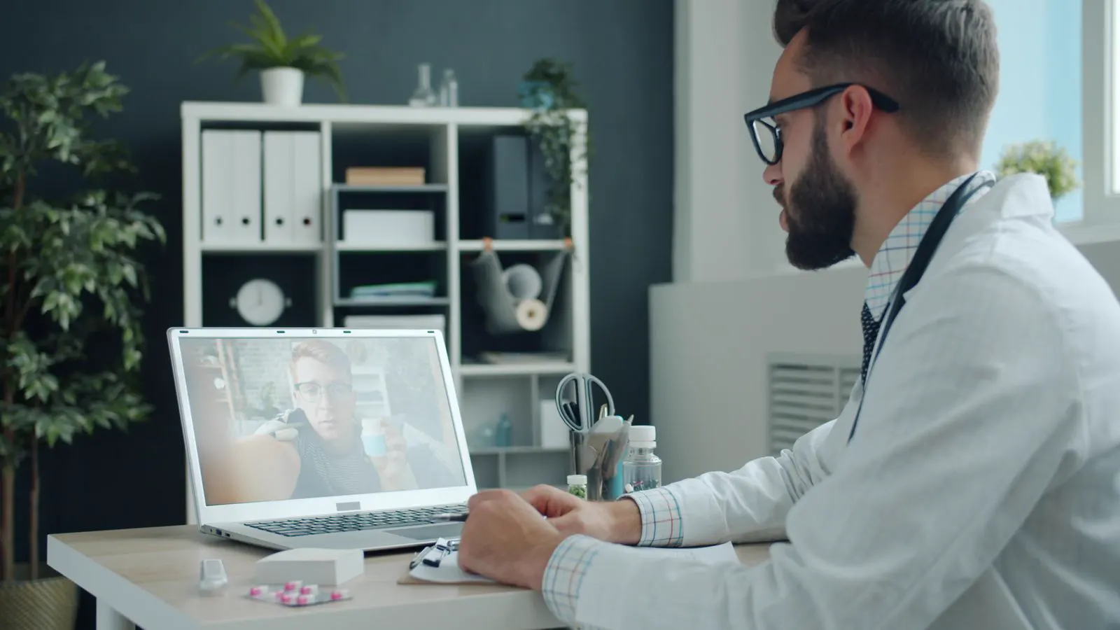 Médico atende paciente por videochamada no notebook em teleconsulta